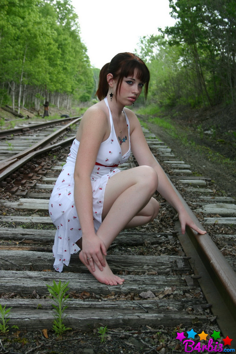 Девушка в белом сарафане фотографируется на железнодорожных путях
